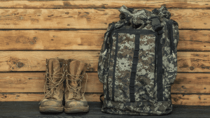 A pair of military-style boots next to a camouflage rucksack