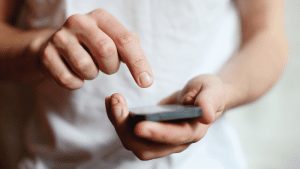 Image of a man holding a mobile phone typing.