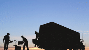 Movers unloading a moving truck. The sun is setting in the background.